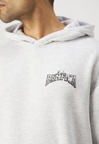Light gray hoodie with a soft texture, featuring a black "BENFICA" logo stitched on the front. The design includes a hood and ribbed neckline.
