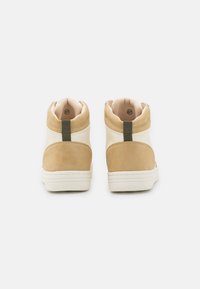 Weiße und beige High-Top-Sneaker mit glatter Oberfläche, strukturierten beige Wildlederakzenten und einer grünen Zuglasche an der Ferse. Größe 37.