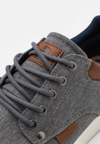 Sneaker in tessuto grigio con accenti in pelle, lacci rotondi, occhielli in metallo e soletta imbottita. Design testurizzato con dettagli di colore a contrasto.