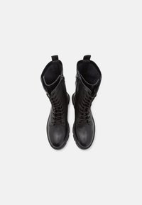 Botas de tobillo de cuero negro con un acabado suave, que cuentan con cordones y cierre de cremallera. Punta redondeada y forro interior texturizado.