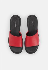 Røde skinnesandaler med bred stropp og svart såle. Designet har en jevn tekstur og en firkantet tåform.