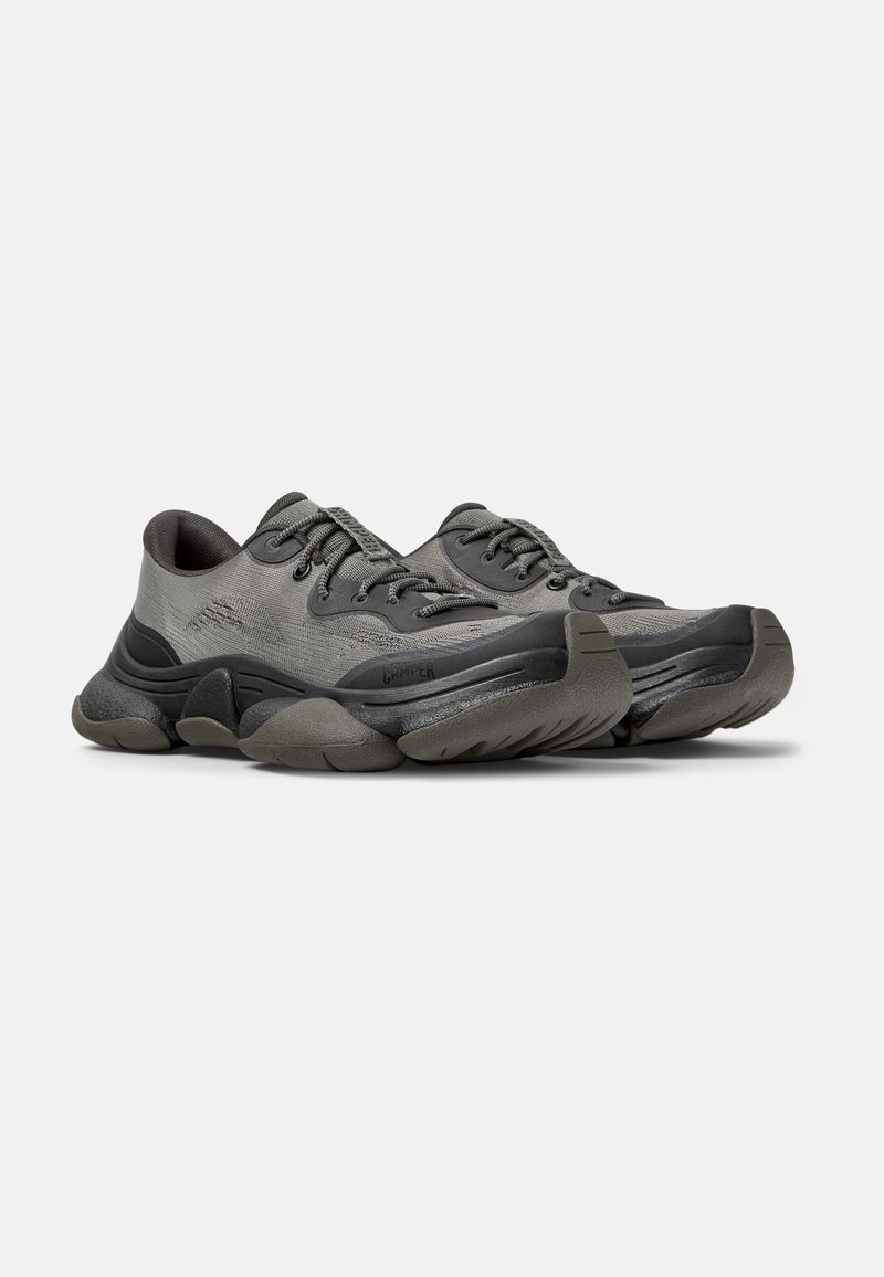 Graue Sneaker mit einer strukturierten Oberseite, abgerundeter Zehenpartie, dickem Gummisole und ausgeprägten Akzenten an der Seite und Ferse.