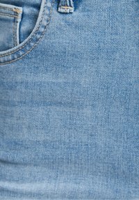 Jeans de mezclilla azul claro con un bolsillo frontal, costuras visibles y una textura ligeramente desgastada, que muestran un diseño estándar de jeans.