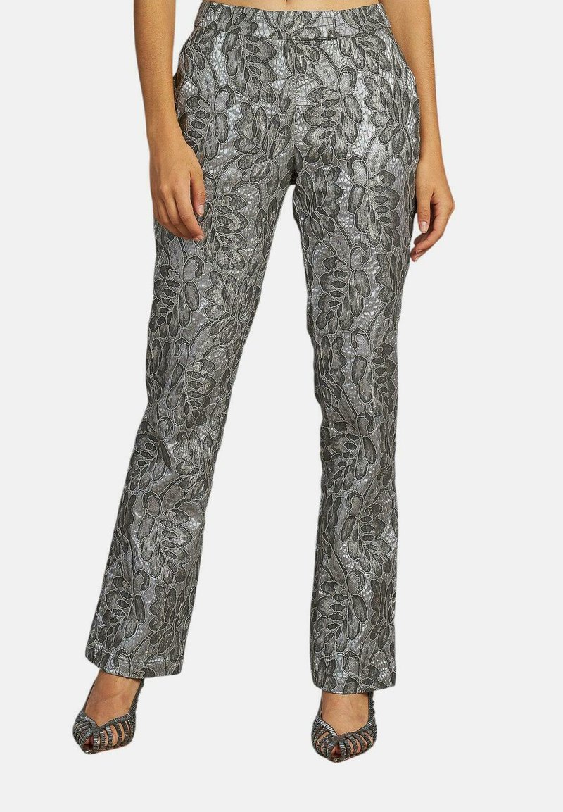 Metalen zilveren broek met ingewikkelde bloemmotieven, ontwerp met rechte pijpen en een elastische tailleband. Gecombineerd met zwarte open teenschoenen.
