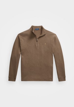 Brūns džemperis ar rāvējslēdzēja apkakli. Ribotas aproces, maiga tekstūra un neliels logotipa akcents uz krūtīm. Kokvilnas slāņojuma materiāls.