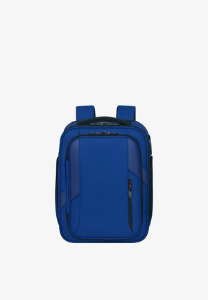 Blue rectangular soft-sided backpack with padded straps, multiple zippered compartments, and a small black and red logo tag on the front pocket.