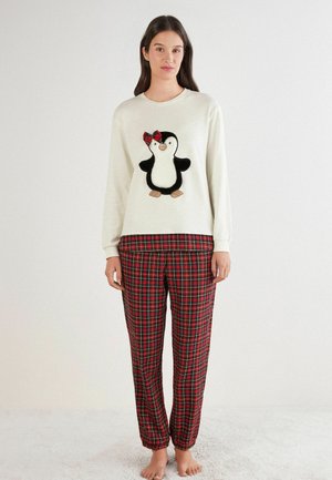 Kremowa bluza z wzorem pingwina, ozdobiona czerwoną, szkocką kokardą. Spodnie piżamowe w czerwono-zieloną kratę z elastycznymi ściągaczami.