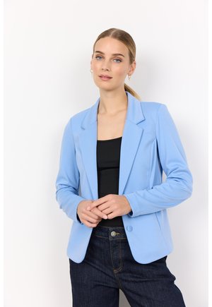 Svetlomodrý blazer s klopovým golierom, uzatváraním na jediný gombík a prispôsobeným strihom, nosený cez čierny top a tmavé džínsy.