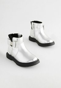 Silberne metallische Knöchelstiefel mit glatter Oberfläche, schwarzen elastischen seitlichen Einsätzen, einem kleinen Schleifenakzent und schwarzen Gummisohlen.