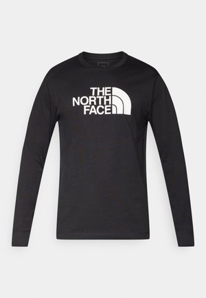 Long-sleeve black t-shirt made of cotton, featuring a prominent white logo of "The North Face" across the chest in a bold font.