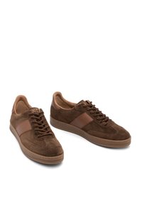 Brown suede sneakers with leather side stripe, round toe, and brown patterned laces, shown on white background.