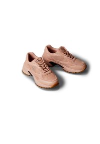 Par de zapatillas Calvin Klein de color rosa claro con detalles de malla y gamuza, suelas gruesas y cordones, proyectando sombras sobre un fondo blanco.