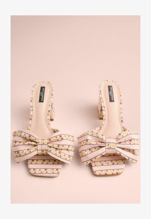 Mule z odprtim prstom, ki ima rožnato-belo črtasto tkanino z rožnatimi vzorci, velikim lokom spredaj in kvadratno peto.