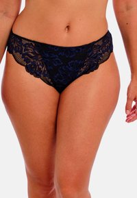 Musta pitsialushousu, jossa on sininen kukkakuosi, aaltoilevat reunat ja pehmeä kangas. Keskikorkea malli, jossa on minimaalinen peittävyys.