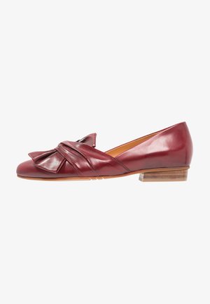 Chaussure plate pour femme en cuir bordeaux avec un petit talon en bois et un nœud torsadé décoratif sur le devant.