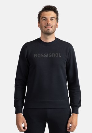 Felpa nera con polsini e orlo a coste, collo tondo e la scritta "ROSSIGNOL" stampata in modo evidente sul davanti. Texture liscia.
