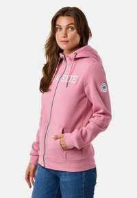 Rosa Zip-Hoodie mit frontalen Taschen, Kordelzugkapuze und weißem "SEA SIDE"-Grafik. Weicher Stoff, gerippte Bündchen und Logopatch am Ärmel.