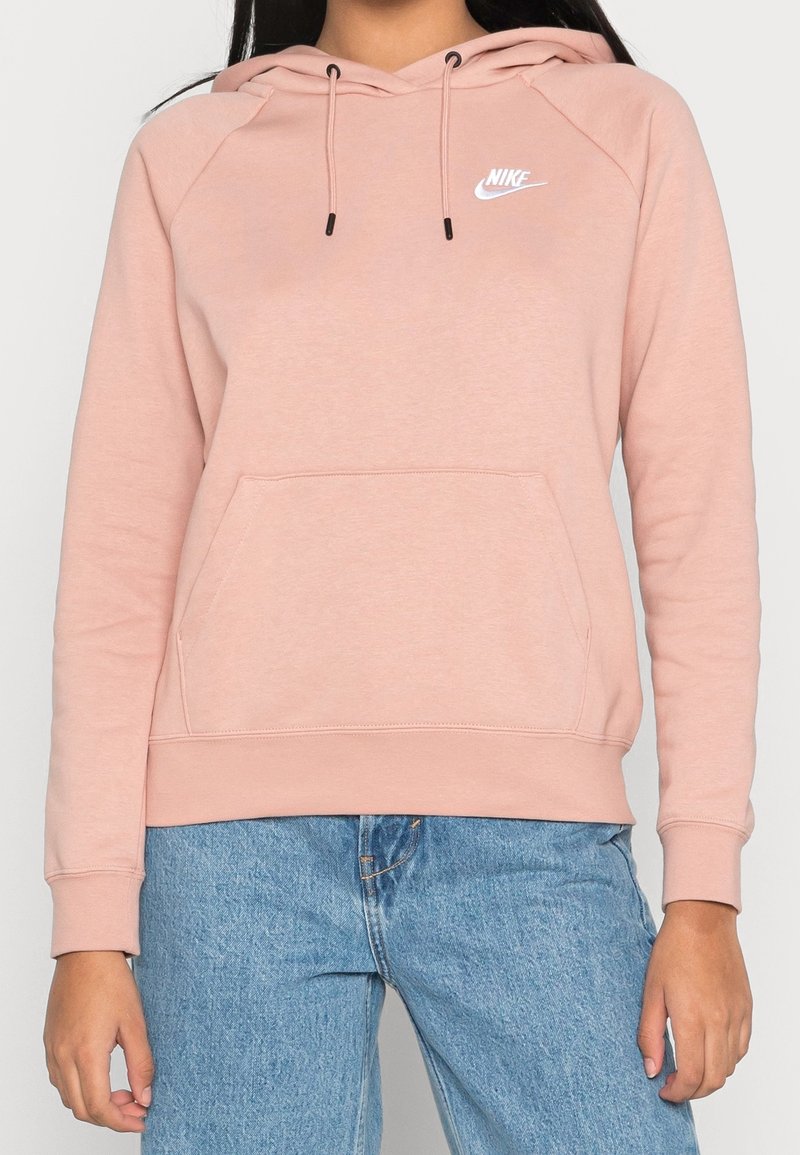 Lichtroze Nike-hoodie met koordjes, kangoeroezak en geribbelde manchetten. Voorzien van een klein wit logo op de bovenkant van de borst. Zacht materiaal.
