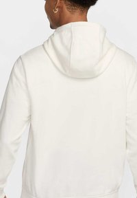 Felpa bianca con cappuccio regolabile, caratterizzata da una texture morbida, maniche lunghe e una vestibilità comoda. Design minimalista senza motivi visibili.