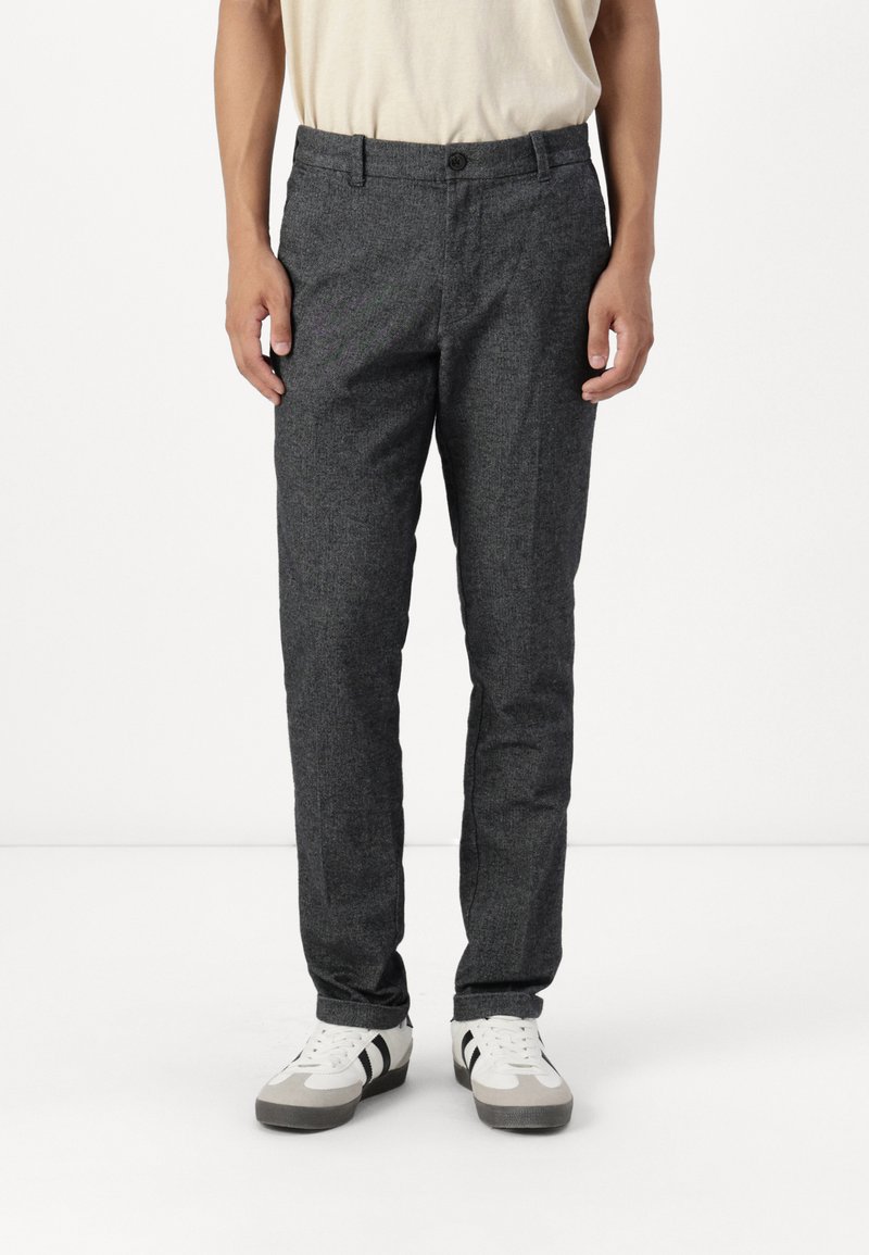 Grau strukturierte Hose mit geradem Schnitt, mit Knopfverschluss und Gürtelschlaufen, kombiniert mit weißen und grauen Sneakers.