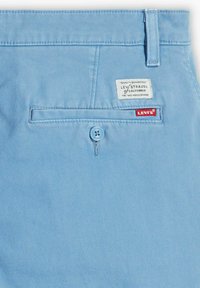 Jasnoniebieska bawełniana tkanina z tylną kieszenią, z zapięciem na guzik i metką z napisem "Levi Strauss California" oraz czerwoną etykietą "Levi's".