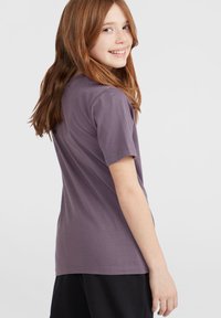 T-shirt z krótkim rękawem w kolorze lawendowym, wykonana z miękkiego materiału bawełnianego, z okrągłym dekoltem i prostym wzornictwem bez nadruków.