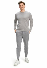 Grauer Langarmpullover und passende Jogginghosen aus weichem Stoff. Weiße Sneakers vervollständigen das Outfit. Sauberes, minimalistisches Design mit körperbetonter Silhouette.