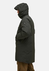 Mörkgrön isolerad parkas med huva, utrustad med en framfick zipp, sidofickor och en slät, vattenavvisande yta.