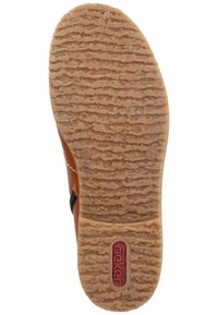 Semelle en caoutchouc marron avec des rainures texturées, arborant un accent rouge marqué. La forme de la semelle extérieure est ovale avec des bords arrondis.