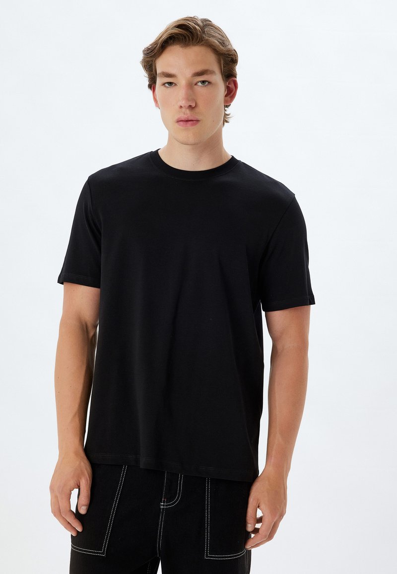 Sort t-shirt i blødt stof med klassisk rund hals og korte ærmer. Sammen med sorte jeans med hvide syninger.