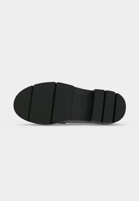 Semelle de chaussure noire avec de profondes rainures horizontales et le nom de la marque ALDO embossé au centre.
