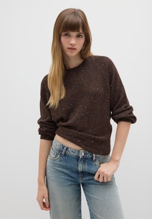 Maglione a maglia marrone scintillante con scollo a rotondo, maniche ampie e vestibilità cropped, abbinato a jeans azzurri a vita alta.