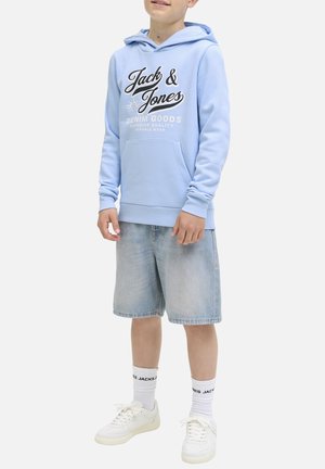 Hoodie bleu clair avec logo noir et texte blanc, poche kangourou, poignets côtelés, associé à un short en denim et des baskets blanches.