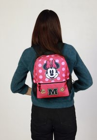 Mochila roja y rosa con lunares y un gráfico de Minnie Mouse, con un bolsillo frontal y correas ajustables. Tejido texturizado.