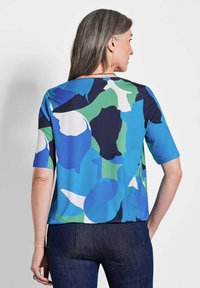 Kurzärmlige Bluse in blau, grün und marineblauem abstraktem Muster. Sanfter Stoff mit lockerer Passform. Der Rücken hat einen runden Ausschnitt.
