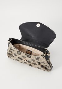 Béžová látková kabelka s černými doplňky, s logovým vzorem, magnetickým zapínáním a vnitřním zipovým kapsou. Hladká textura.