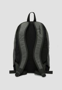 Mochila negra y gris con correas y panel trasero acolchados, que cuenta con correas ajustables y un discreto logotipo en el costado. Textura de tela duradera.
