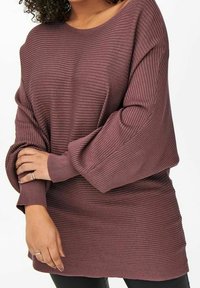 Överdimensionerad vinröd stickad tröja med horisontell ribbad textur, bred halsringning och långa ärmar. Mjuk tyg med avslappnad passform.