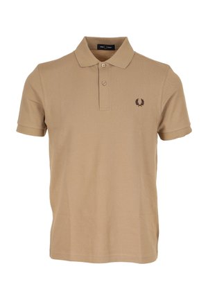 Polo beige en coton, avec une patte de boutonnage à deux boutons, des manches courtes et un logo brodé en marron foncé sur la poitrine gauche.