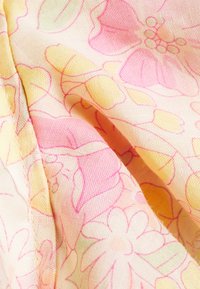 Tessuto di cotone con un motivo floreale in rosa chiaro e giallo, caratterizzato da delicate linee contornanti fiori e foglie su uno sfondo morbido.