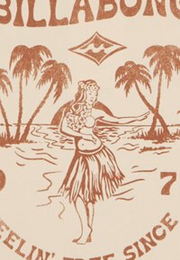 Grafika Billabong przedstawia brązowy rysunek hawajskiej tancerki w spódnicy z trawy, otoczonej palmami i falami oceanu na kremowym tle.