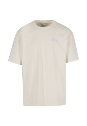 Kermainen puuvillainen t-paita, jossa on pyöreä pääntie ja lyhyet hihat, vasemmassa rinnassa pieni sininen kirjailtu logo.