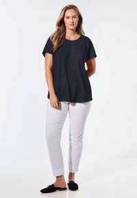 Marineblauw T-shirt met korte mouwen en ronde hals, gecombineerd met witte tapered broek en zwarte instappers. Vlotte textuur, casual pasvorm.