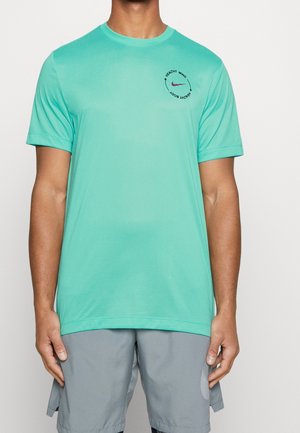 Man draagt een turquoise, korte mouw sportshirt met de tekst "Healthy Mind Healthy Body" en een klein bordeauxrood swoosh-logo op de borst.