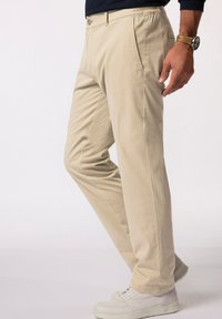 Beiga bomullsshorts med raka ben, med sidofickor och elastisk midja, i kombination med vita sneakers.