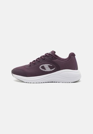 Zapatilla deportiva púrpura con parte superior de malla, punta redonda y suela de goma blanca. Presenta un logo prominente y acentos texturizados en la parte superior.