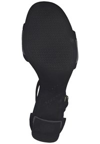 Czarna gumowa podeszwa buta z teksturowanym wzorem, z szerokim obcasem i otwartym designem, odpowiednia do różnych powierzchni chodnikowych.