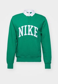 Grön Nike-huvtröja med vit krage, stort vitt logotyp, kenguruficka, ribbad manschett och fåll. Mjuk textur och avslappnad passform.