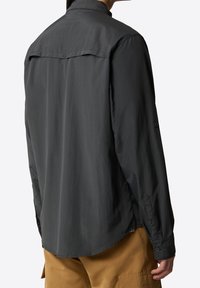 Camicia grigia a maniche lunghe con taglio dritto, polsini con bottoni e yoke posteriore. Realizzata in tessuto leggero. Presenta una texture liscia.