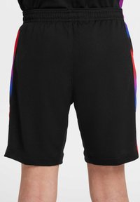 Shorts noirs en tissu texturé, avec des rayures en dégradé de couleurs rouge, violet et bleu sur le côté. Taille élastique.